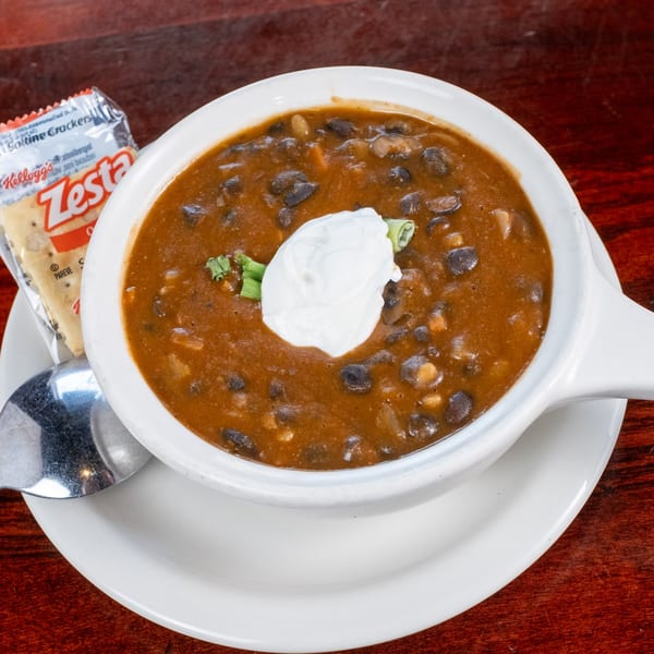 A bowl of Bullwinkle's Top Hat Bistro's black bean soup with sour cream and crackers.