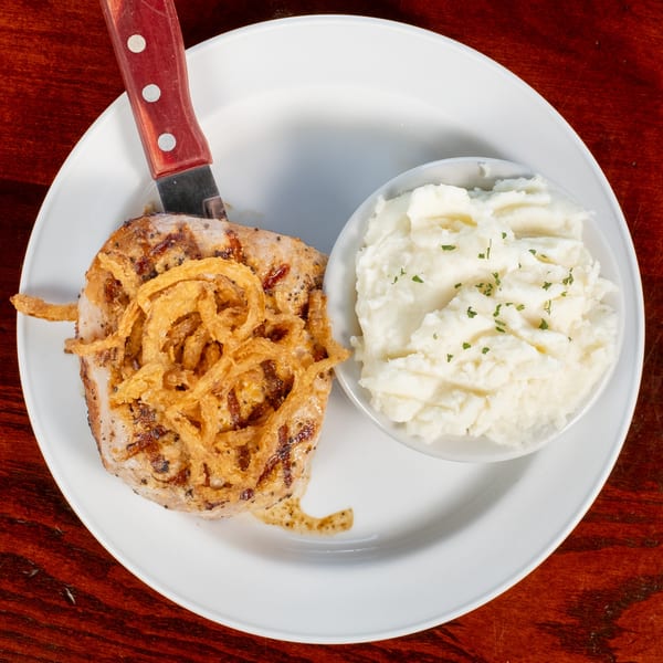 Bullwinkle's grilled pork chop topped with crispy fried onions, served with mashed potatoes.